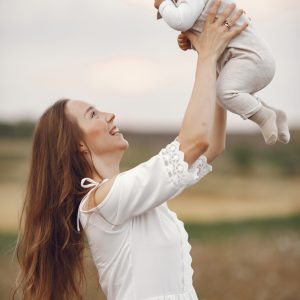 Mother with daughter. Family in a field. Newborn girl. Woman in a white dress.