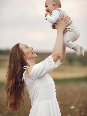 Mother with daughter. Family in a field. Newborn girl. Woman in a white dress.