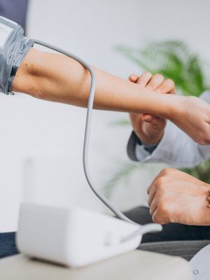 Young male psysician with patient measuring blood pressure